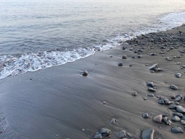 Kumsalda su dalgaları Gri kum ve mercan taşlarıyla