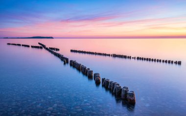 Wooden breakwaters pointing towards the sunset in Dranske, Ruegen, Germany. High quality photo clipart