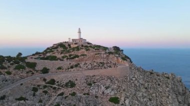 Bir deniz feneri dağın tepesinde duruyor, aşağıdaki engin okyanusun geniş manzarasını sunuyor..