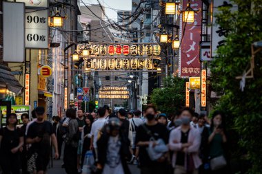 Kalabalık kalabalık kalabalık bir caddede ellerinde 90c ve 60c yazan tabelalarla yürüyorlar. Tokyo şehir merkezinde.