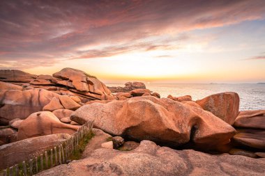 Gün batımında pürüzsüz pembe granit kayaların muhteşem bir manzarası. Huzurlu ve huzurlu bir sahil şeridi boyunca.