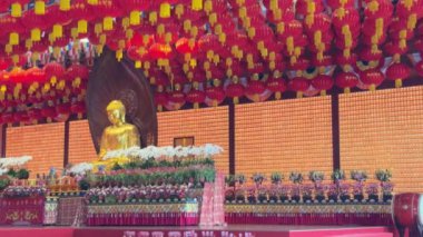 Huzurlu bir Buda heykeli, barış ve bağlılığı simgeleyen canlı ve renkli fenerlerle süslenir.