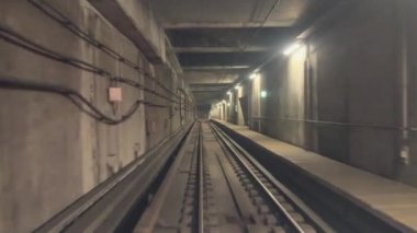 Yumuşak ortam aydınlatması içeren boş bir metro tünelinin büyüleyici ve ilgi çekici bir perspektifi.