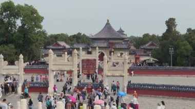 Yeşillik ve çeşitli ziyaretçilerin parkın tadını çıkardığı tarihi bir kapıda hareketli bir manzara..