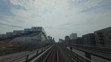 Geniş ve geniş manzaralı demiryolu rayları şık ve modern kentsel binalarla güzel çerçevelenmiş.