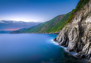 Bu çarpıcı sahil şeridi alacakaranlıkta dingin bir deniz manzarasına karşı yüksek uçurumlar sergiliyor. Yumuşak dalgalar kayalık sahilde süzülür, sakin bir atmosfer yaratır..