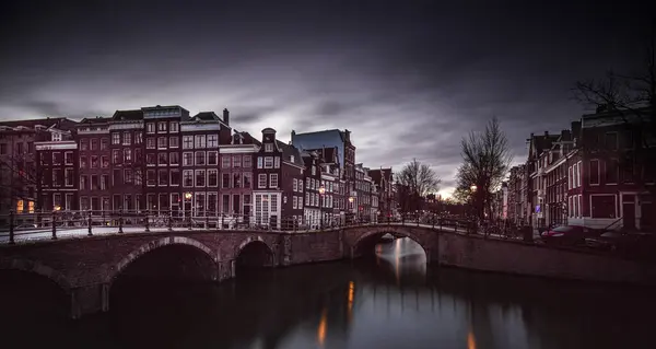 Akşam ışığı Amsterdam 'ın kanallarını kaplayan tarihi binaların üzerinde güzel bir parıltı salıyor. Gündüzün geceye dönüşmesi gibi sakin suda yansımalar parıldıyor..
