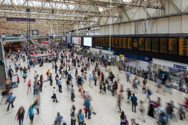 Kalabalık gezginler hareketli bir tren istasyonunda hareketli saatlerde yoğun terminalde dolaşırken dijital panolardan kalkış kontrollerini yapıyorlar..