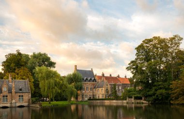 Güzel tarihi binalar, Brugge 'de günbatımında sakin suları yansıtarak sakin bir atmosfer yaratırlar. Yeşillik bölgeyi çevreleyerek cazibesini ve huzurunu artırıyor..