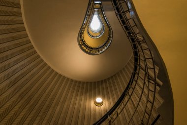 Karmaşık spiral merdiven, Prag 'daki tarihi bir binanın mimari güzelliğini gözler önüne seren, tepede parlayan bir ışığa çıkan dolambaçlı bir tasarım içeriyor..