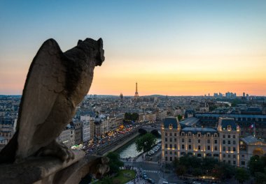 Yüksek bir bakış açısından, bir heykel güneş batarken Paris ufuk çizgisini izliyor. Parlayan alacakaranlık ikonik Eyfel Kulesi 'ni ve aşağıdaki büyüleyici şehir sokaklarını aydınlatıyor..