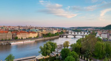 Akşam ışığı Prag 'ı sıcak bir şekilde aydınlatarak, Vltava Nehri' ni çevreleyen tarihi binaları vurguluyor. Köprüler canlı şehri birbirine bağlıyor, mimari güzelliğini sergiliyor..