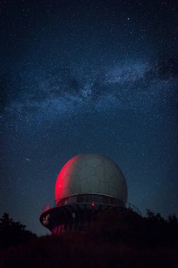 Bir gözlemevinin parlak kırmızı kubbesi yıldızlı gece gökyüzünü yakalar, Samanyolu ise başımızın üstünde uzanır ve çarpıcı bir gökyüzü oluşturur..