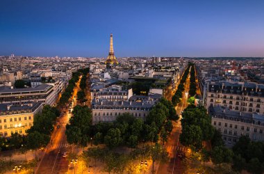 Paris 'in göz kamaştırıcı gece manzarası Eyfel Kulesi' nin güzel aydınlatılmış caddelerin arasında ayakta durduğunu gösteriyor. Gökyüzü alacakaranlıktan geceye geçiyor, şehrin cazibesini vurguluyor..