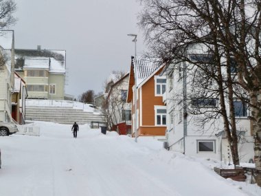 Bir kayakçı, sakin bir ocak günü Tromso 'nun yerleşim bölgesindeki bu yamaca tırmanırken evine dönüyor..