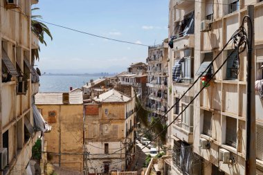 High rise apartment buildings housing multiple families line the stairs down the hill to the harbor in Algiers. clipart