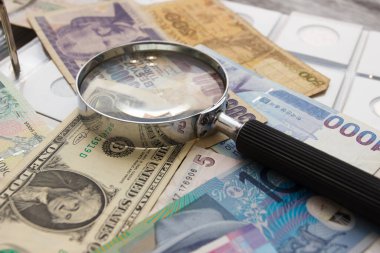 Farklı eski koleksiyoncu paraları ve büyüteç, yumuşak odaklı arka plan