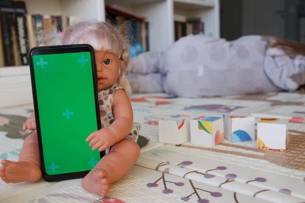 Smartphone with a green screen. Concept of education online. Little kid with toys in the playroom