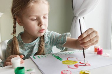 Little child draws with watercolor, concept of education in the kindergarten, soft focus background