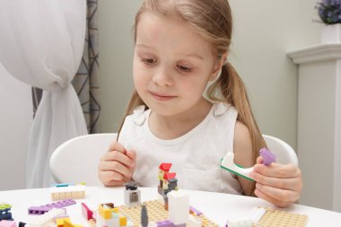 Çocuk inşaatçı tuğlalarıyla, oyuncaklarla oynar, yumuşak odaklı arka planla çalışır