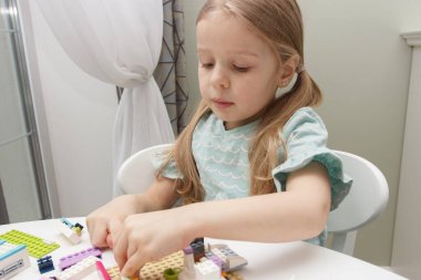 Çocuk inşaatçı tuğlalarıyla, oyuncaklarla oynar, yumuşak odaklı arka planla çalışır