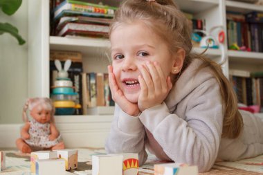 Little cute girl reading a book in the room, soft focus background. Education at home concept.
