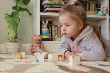 Little cute girl reading a book in the room, soft focus background. Education at home concept.