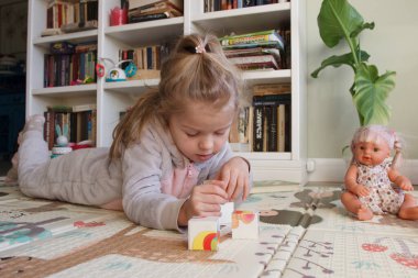 Little cute girl reading a book in the room, soft focus background. Education at home concept.