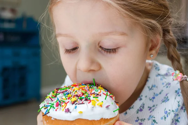 stock image Cute little girl tasting a cake with colored sweet decorations