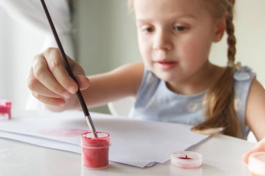 Little child draws with watercolor, concept of education in the kindergarten, soft focus background