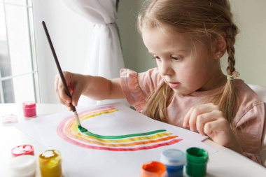 Little child draws with watercolor, concept of education in the kindergarten, soft focus background