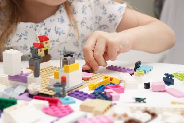 Child builds with constructor bricks, plays with toys, soft focus background