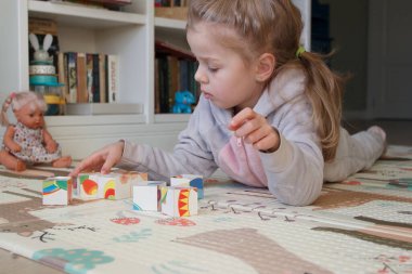Little cute girl reading a book in the room, soft focus background. Education at home concept.