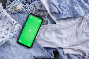 Cebinde Amerikan doları olan mavi kot pantolon ve yeşil ekranlı bir akıllı telefon. Seyahat ya da alışveriş kavramı