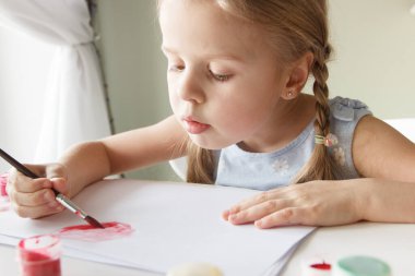 Little child draws with watercolor, concept of education in the kindergarten, soft focus background