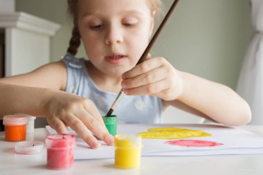 Little child draws with watercolor, concept of education in the kindergarten, soft focus background