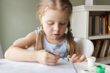 Little child draws with watercolor, concept of education in the kindergarten, soft focus background