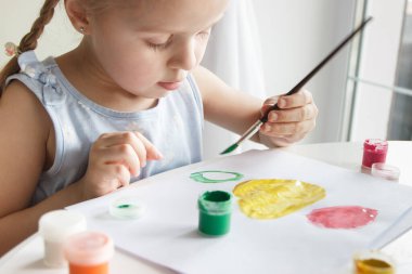 Little child draws with watercolor, concept of education in the kindergarten, soft focus background