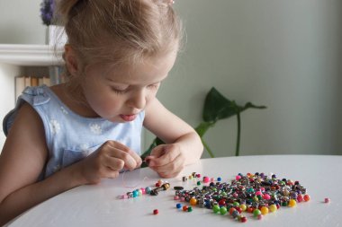 İplik ve renkli boncuklardan bilezik yapma süreci, hobi ya da eğlence kavramı
