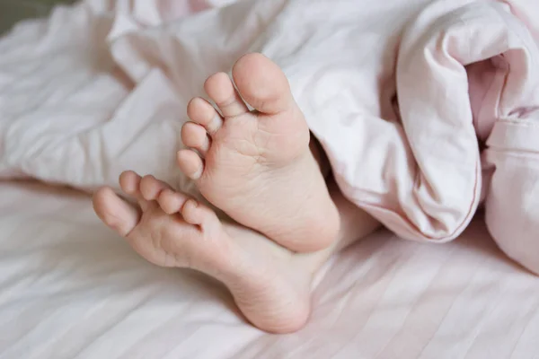 ベッドの上に軽い毛布の下の足 朝の眠りや目覚めの概念 — ストック写真