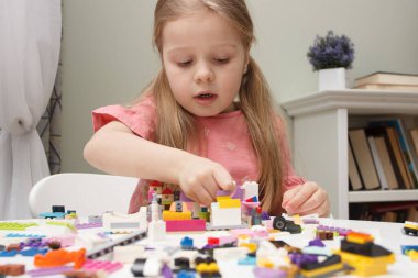 Çocuk inşaatçı tuğlalarıyla, oyuncaklarla oynar, yumuşak odaklı arka planla çalışır