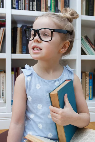 本棚の前に座っている眼鏡の中の可愛い女の子 図書館教育の考え方 — ストック写真