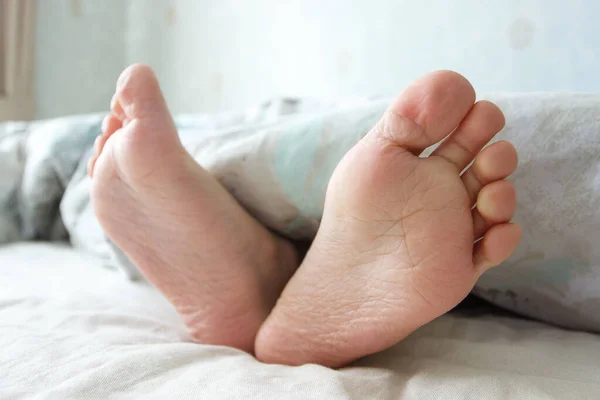 ベッドの上に軽い毛布の下の足 朝の眠りや目覚めの概念 — ストック写真