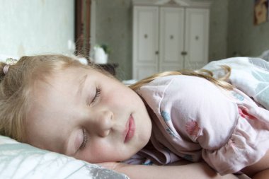 Yatakta yatan küçük tatlı kız. Sabah uyanma kavramı.