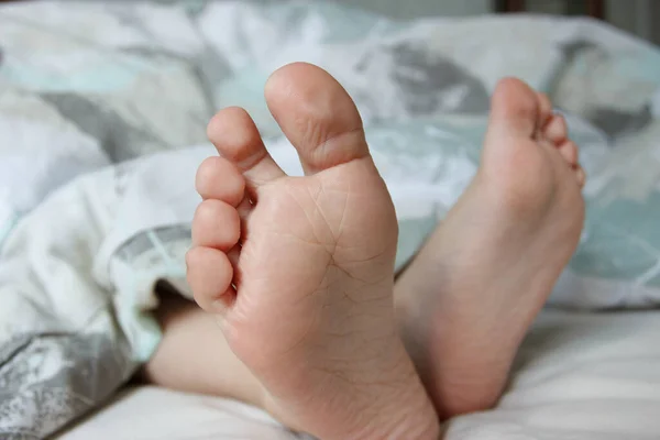 ベッドの上に軽い毛布の下の足 健康と生活様式の概念 — ストック写真