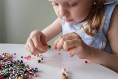 İplik ve renkli boncuklardan bilezik yapma süreci, hobi ya da eğlence kavramı