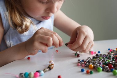 İplik ve renkli boncuklardan bilezik yapma süreci, hobi ya da eğlence kavramı
