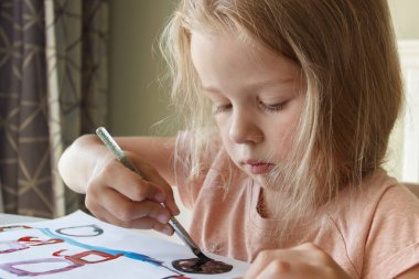 Little child draws with watercolor, concept of education in the kindergarten, soft focus background