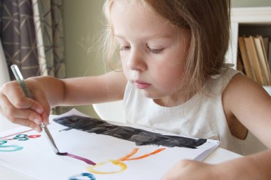 Little child draws with watercolor, concept of education in the kindergarten, soft focus background