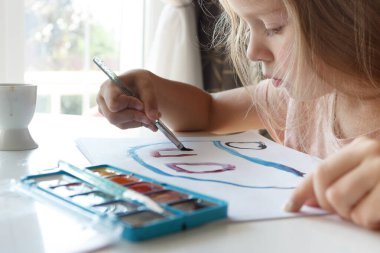 Little child draws with watercolor, concept of education in the kindergarten, soft focus background